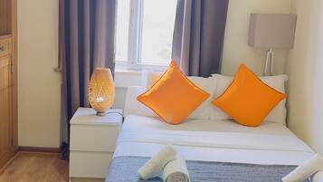 Una camera da letto ordinata con un letto, cuscini, una lampada da comodino e un lampadario.