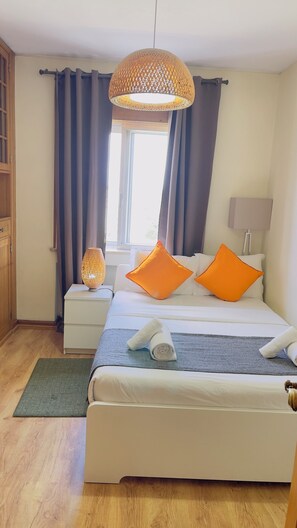 Een netjes ingerichte slaapkamer met een bed, kussens, een bedlampje en een hanglamp.