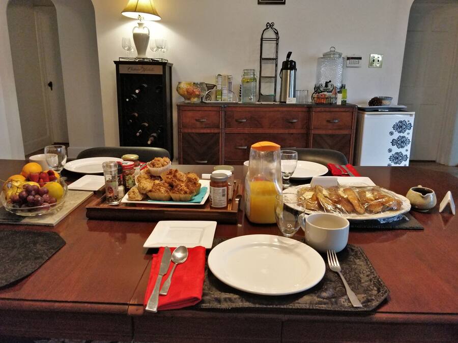 Une table à manger dressée avec des aliments pour le petit-déjeuner, notamment des viennoiseries, des fruits et des boissons.