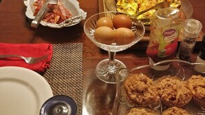 Un bufé de desayuno con diversos platos, incluyendo huevos, tocino y bollería, sobre una mesa de madera.