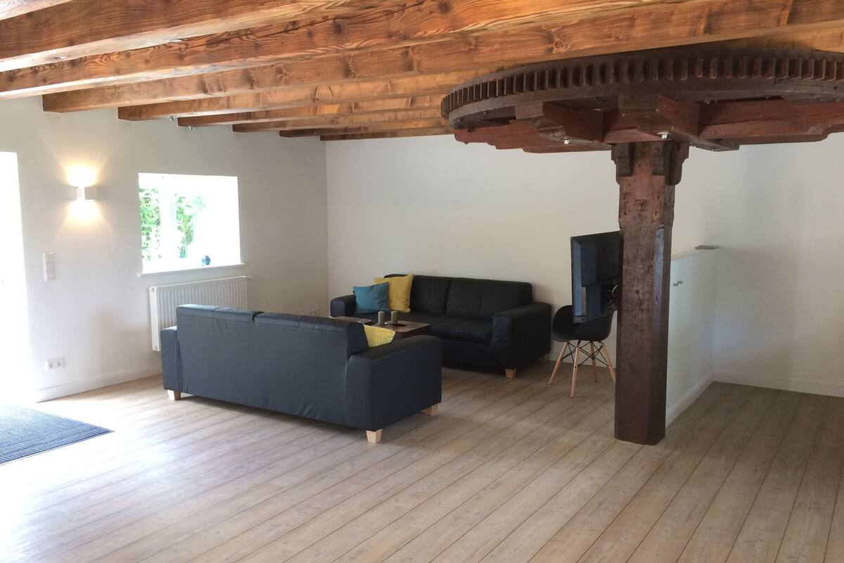 A spacious living area with a wooden ceiling and a large window providing natural light.