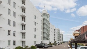 A modern building with multiple floors, large windows, and a cylindrical tower. - Nice and private rooms (London)