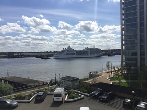 A waterfront view with a cruise ship docked, a parking area, and a modern building. - Nice and private rooms (London)