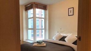 A bedroom with a large bed, a window with blinds, and a framed picture on the wall. - Nice and private rooms (London)
