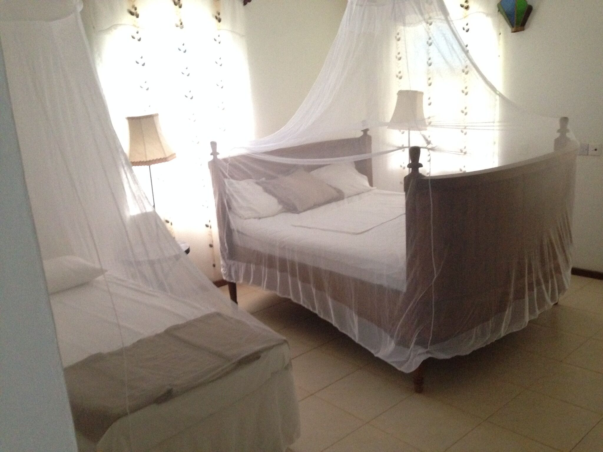 A bedroom with a four-poster bed, a bedside table with a lamp, and a canopy bed.