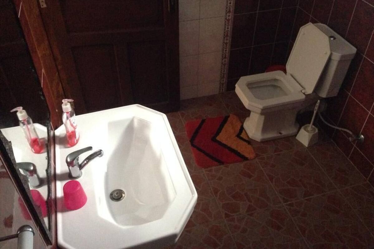A bathroom with a white sink, mirror, and toilet.
