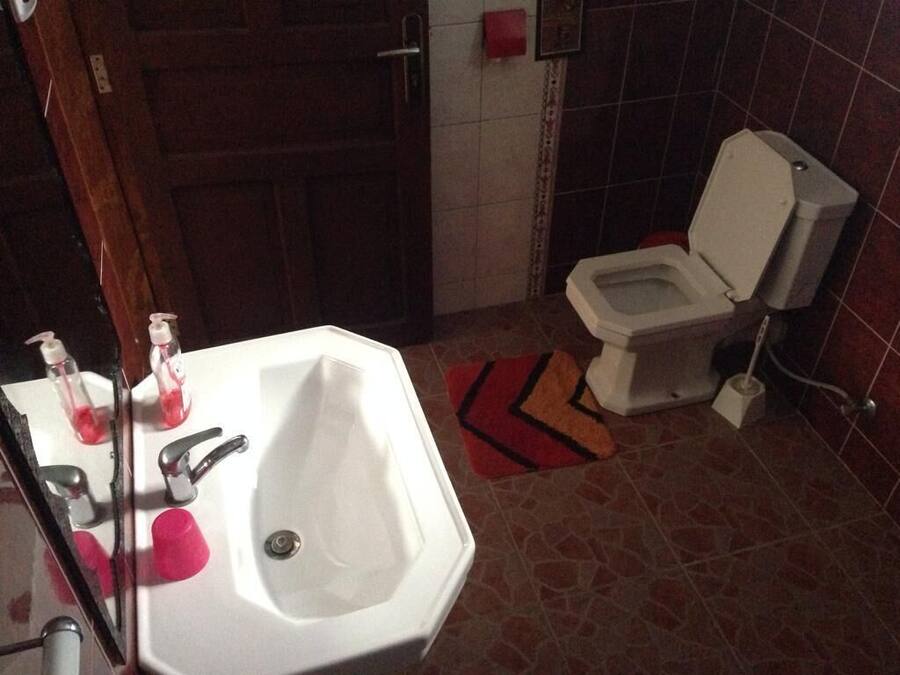 Un baño con lavamanos, espejo y retrete blanco.