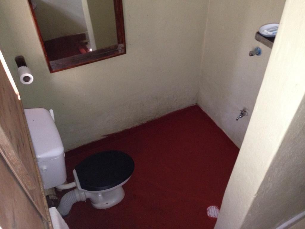 Une petite salle de bain avec des toilettes, un miroir et un sol rouge.