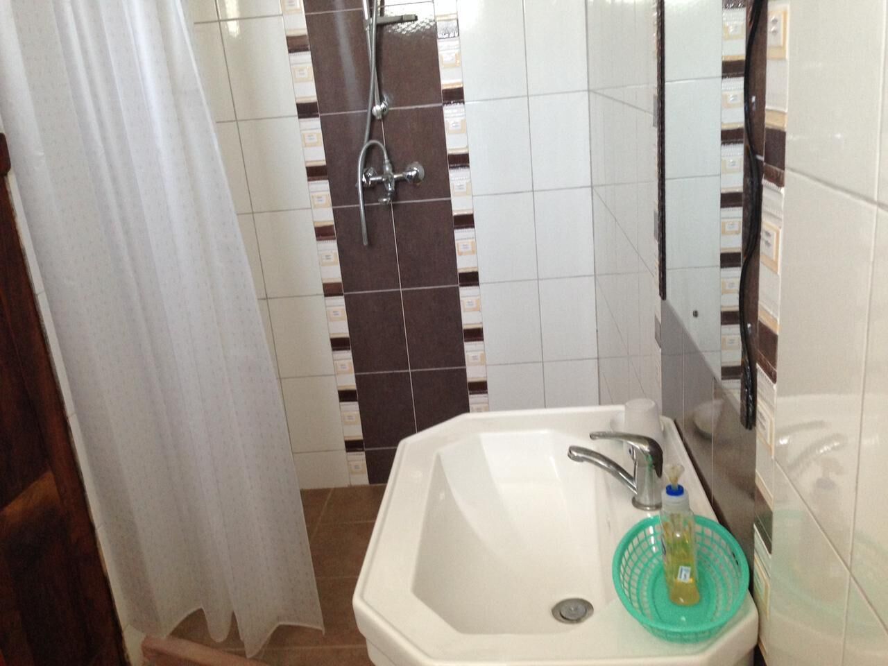 Un baño con lavamanos blanco, ducha y espejo.