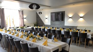A conference room with multiple tables, chairs, and a large screen. - Hotel Am Rathaus (Tangermünde)