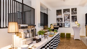 Una mesa de buffet con una estación de café, platos, vasos y un mantel a cuadros.