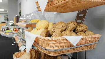 A buffet with various breads and pastries displayed in wicker baskets.
