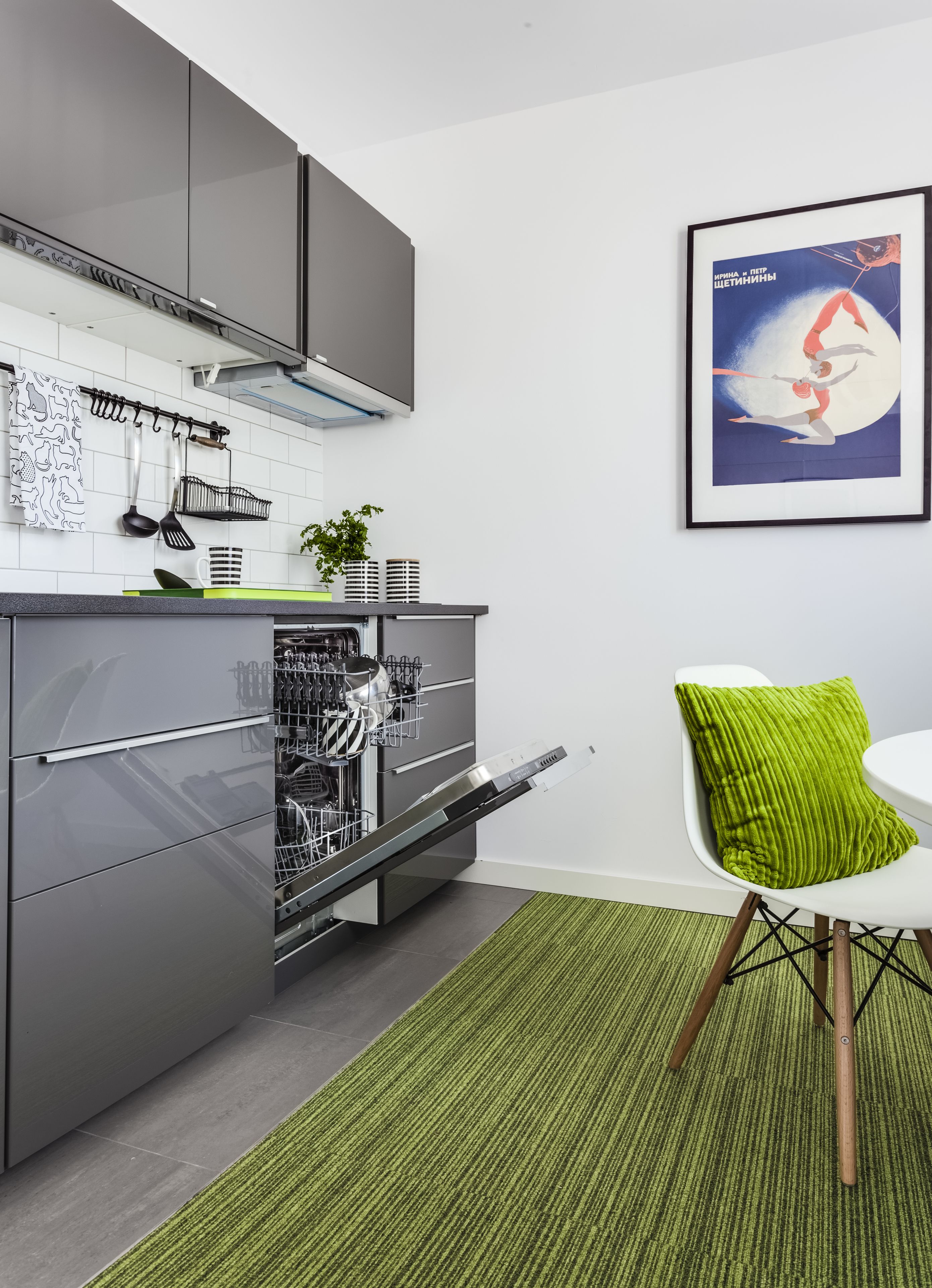 Una cocina moderna con muebles grises, lavavajillas y alfombra verde.