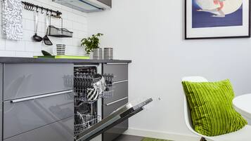 A modern kitchen with grey cabinetry, a dishwasher, and a green rug.