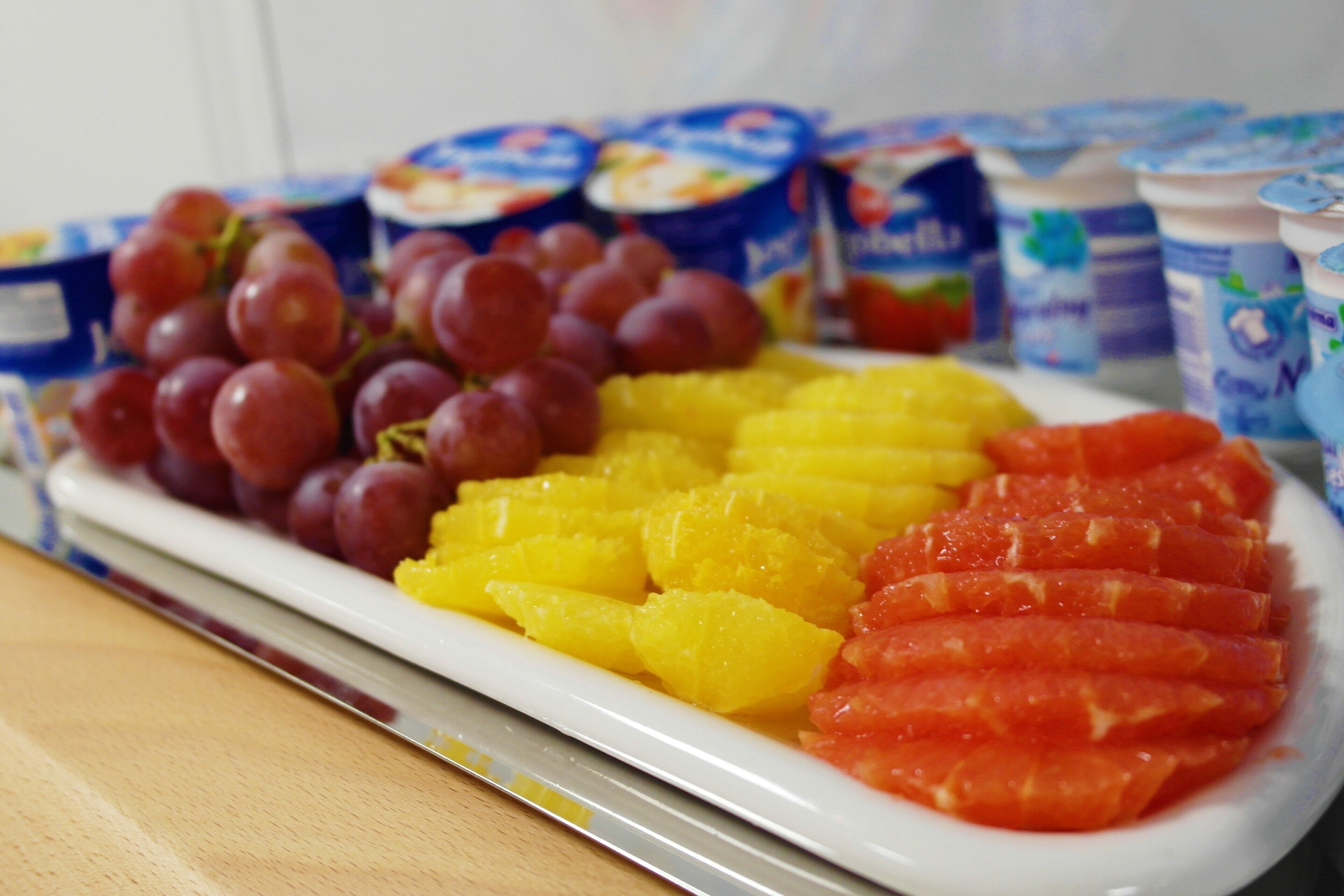 Ein Teller mit Obst und Joghurtbechern.