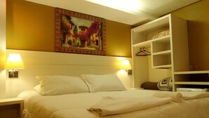 A hotel room with a bed, two bedside lamps, a painting on the wall, a wardrobe, and a bedside table. - Pousada Canela (Canela)