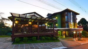A hotel with a covered outdoor area, a second-story balcony, and a well-lit entrance. - Pousada Canela (Canela)