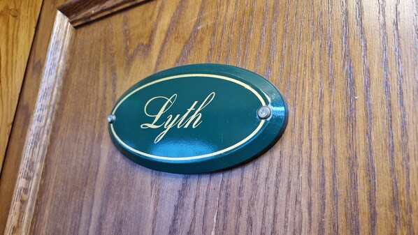 Una porta di legno con una targa ovale verde con scritto "Lyth".