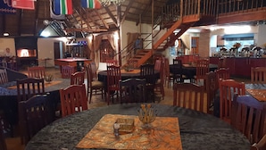 Un amplio espacio interior con varias mesas y sillas para comer, una escalera y una chimenea.