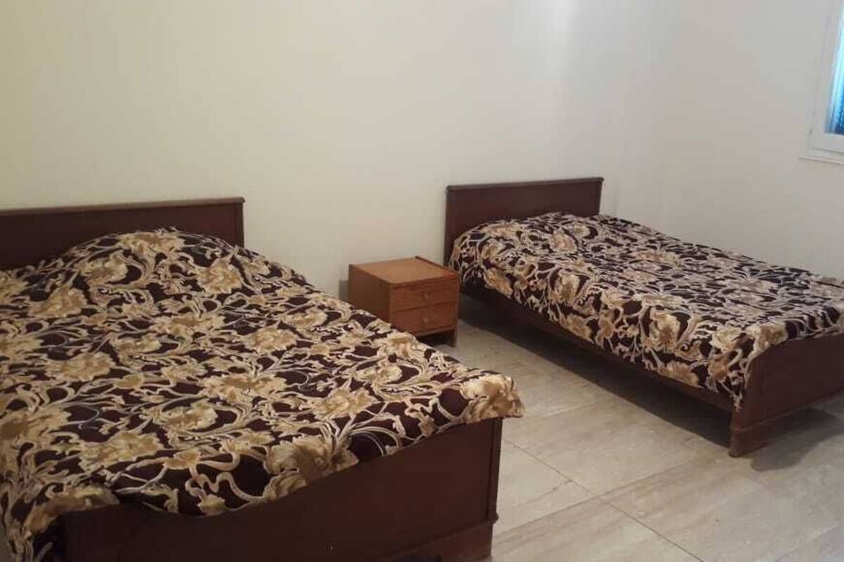 A bedroom with two single beds, a wooden nightstand, and a small wooden chest.