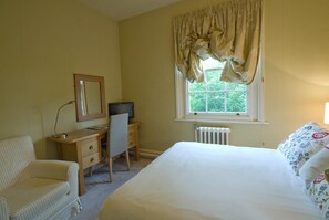 A bedroom with a bed, a desk with a chair, a dresser, a mirror, and a window with curtains. - Peak Weavers Rooms & Restaurant (Leek)