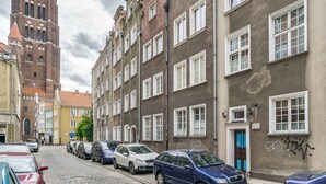 Eine Kopfsteinpflasterstraße, gesäumt von historischen Gebäuden, darunter ein markanter Turm und ein Gebäude mit Graffiti.