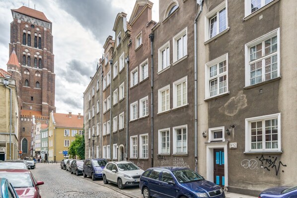 A cobblestone street lined with historic buildings, including a prominent tower and a building with graffiti.