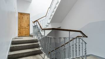 Un escalier avec une main courante en bois et des balustres en métal, menant à une porte en bois.
