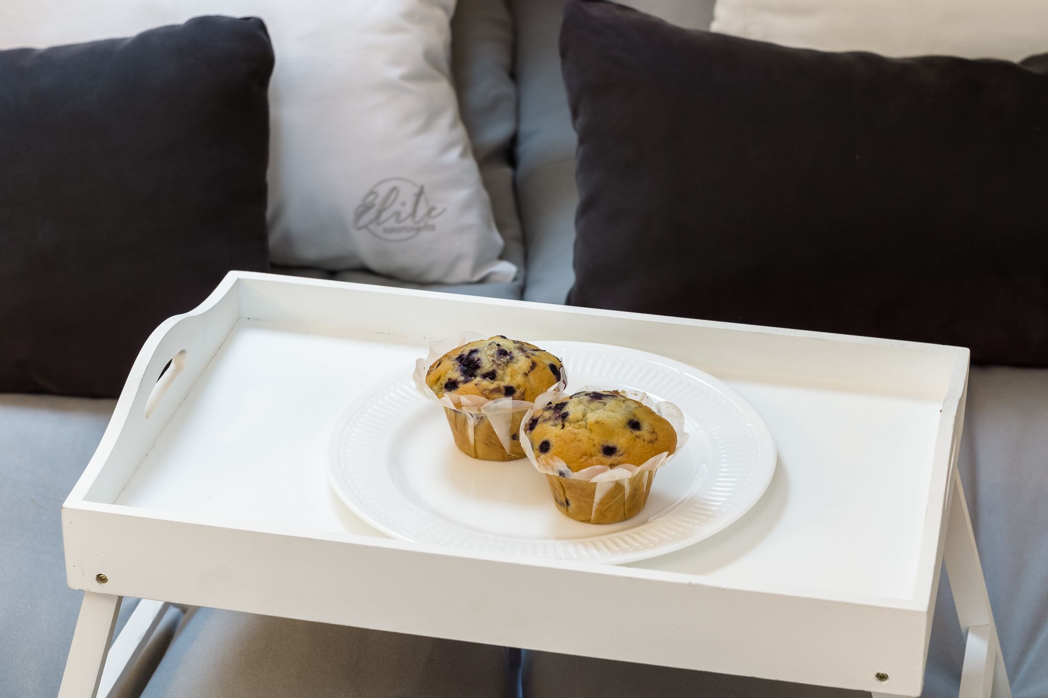 Un plateau avec deux muffins sur une assiette blanche, posé sur une table blanche.