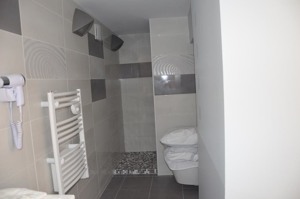 Un baño con inodoro blanco, toallero y zona de ducha con paredes y suelo de azulejos.