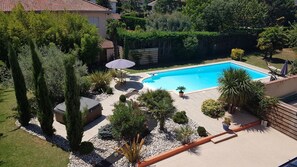A swimming pool surrounded by a garden with various plants and a patio area with seating. - Chambres d'hôtes et Spa (Agen)