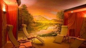 A room with reclining chairs, a mural of a landscape, and curtains. - Hotel Stolberger Hof (Südharz)
