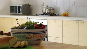 A kitchen with a microwave, stove, and a bowl of fruit on the counter. - Country House Licitra (Ragusa)