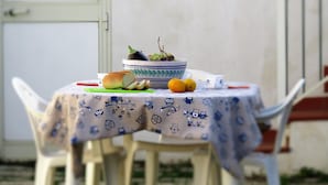 A table with a bowl of fruit, a loaf of bread, and a lemon on a tablecloth with a pattern. - Country House Licitra (Ragusa)