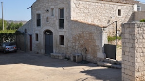 A stone building with a tiled roof, a car parked in front, and a clear sky. - Country House Licitra (Ragusa)