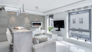 A modern living room with a flat-screen TV, a fireplace, and a large window with a city view. - Elite Apartments Old Town Prestige (Gdansk)