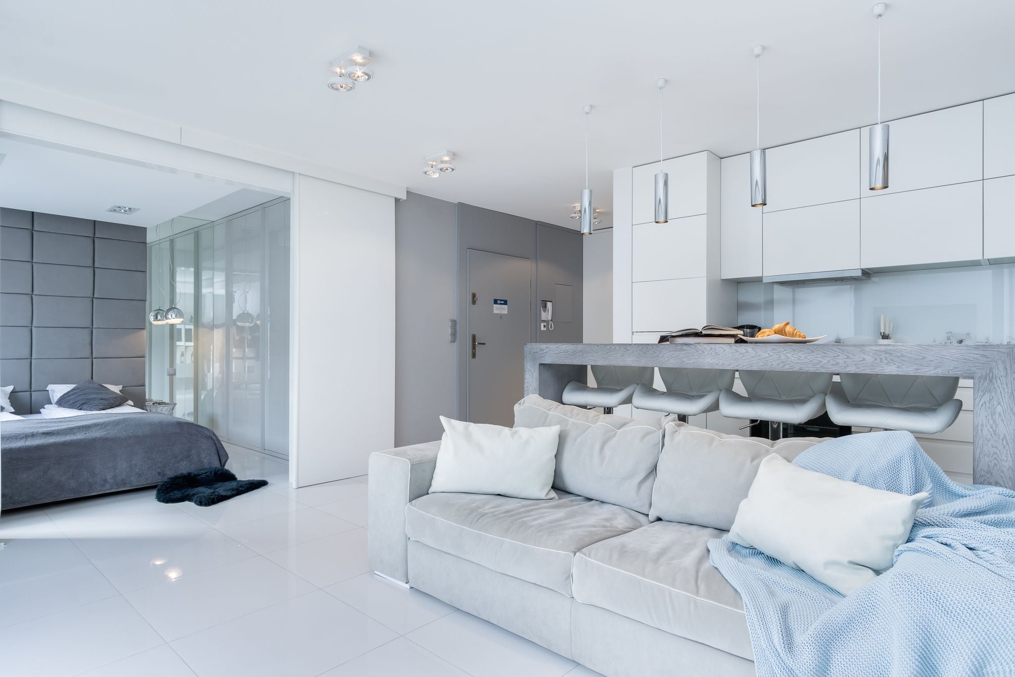 A modern bedroom with a large bed, a sofa, and a built-in bench with storage.