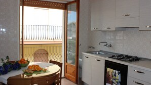 A kitchen with a gas stove, sink, and a dining area with a table and chairs. - Lucy Apartment (Ragusa)
