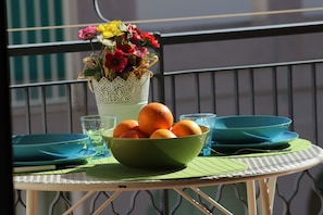 A table with a green bowl of oranges, a vase of flowers, and blue dishes. - Lucy Apartment (Ragusa)