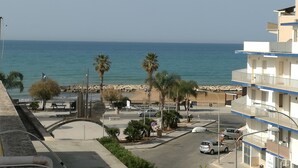 A coastal view with a beach, palm trees, and a parking area. - Lucy Apartment (Ragusa)