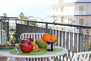 Un balcón con una mesa dispuesta para el desayuno, incluyendo naranjas, un bol y una taza.