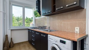 Una cocina moderna con armarios oscuros, una lavadora y un ventanal con vistas a zonas verdes.