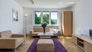 Una sala de estar moderna con un sofá color beige, una mesa de centro, un tapete púrpura, un mueble de madera y un aparador para la televisión.
