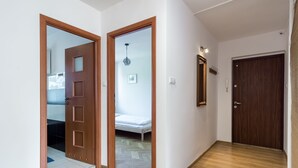 Un pasillo con suelo de madera, una puerta de madera y un espejo en la pared.