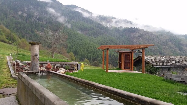 Eine rustikale Holzkonstruktion mit Stein Fundament, einer kleinen Holztür und einem Stein Dach.