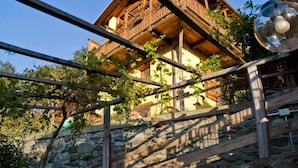 Ein rustikales Holzgebäude mit Balkon, Steinwänden und einer Bank.