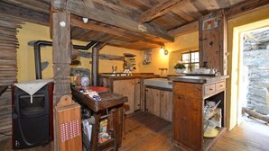 Eine rustikale Küche mit Holzbalken, einer Steinwand und einer kleinen Kücheninsel mit Spüle.