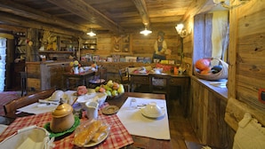 Ein rustikaler Holzraum mit einem Esszimmertisch, der für eine Mahlzeit gedeckt ist, umgeben von Holzwänden und einem Kronleuchter.