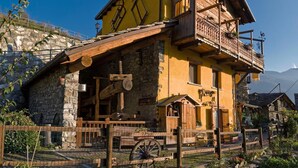 Ein traditionelles Chalet mit Steinfundament, Holzbalkon und rustikalen Innenräumen.