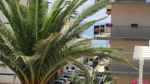 A building with balconies, some with flowers, and a palm tree in the foreground. - Mary Holidays House (Ragusa)